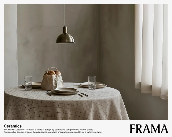 Dining room setup featuring a round table with a checkered tablecloth, plates, glassware, cutlery, a hanging light fixture, and window.