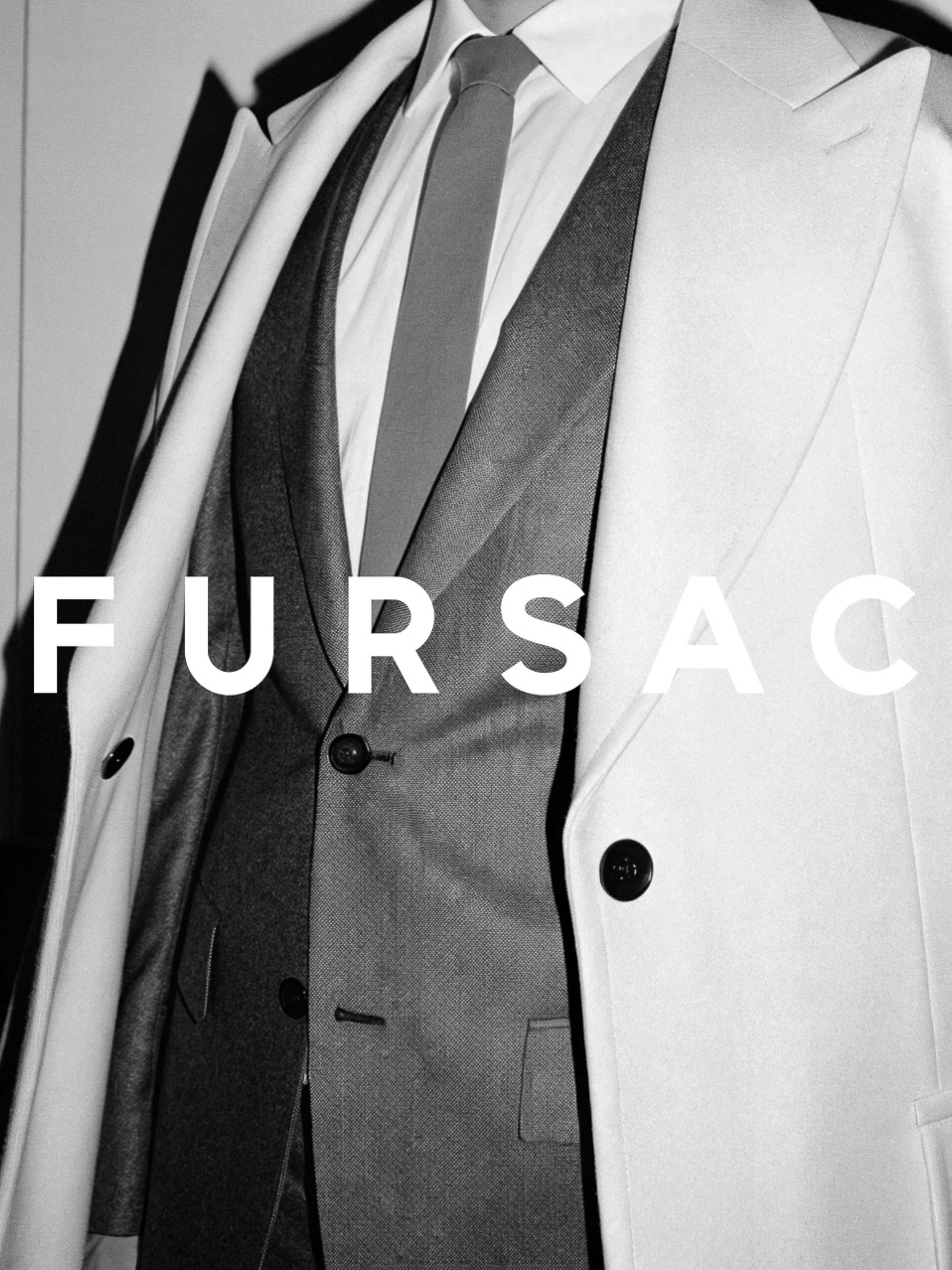 A suit is displayed with a white overcoat in front of a plain backdrop, capturing a sophisticated fashion aesthetic.