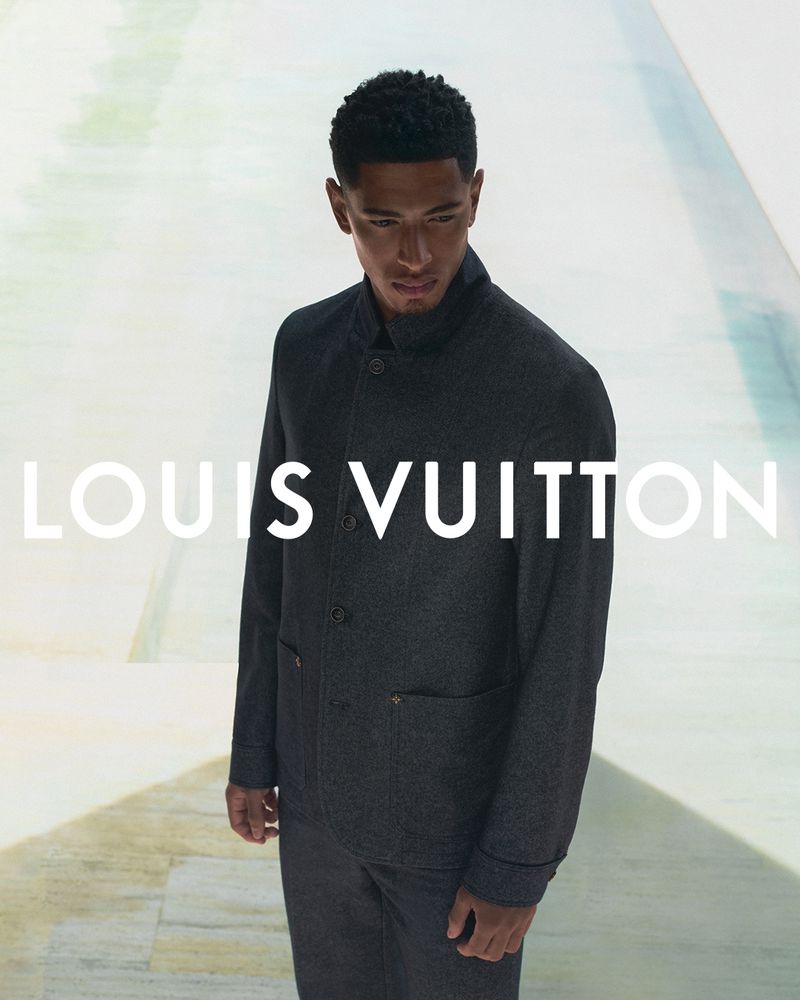Man in a dark button-down jacket stands indoors against an abstract backdrop. The LOUIS VUITTON logo is prominently displayed on the visual.