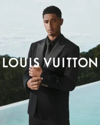 Jude Bellingham wearing a black tuxedo and tie against an outdoor pool and sky background for Louis Vuitton campaign