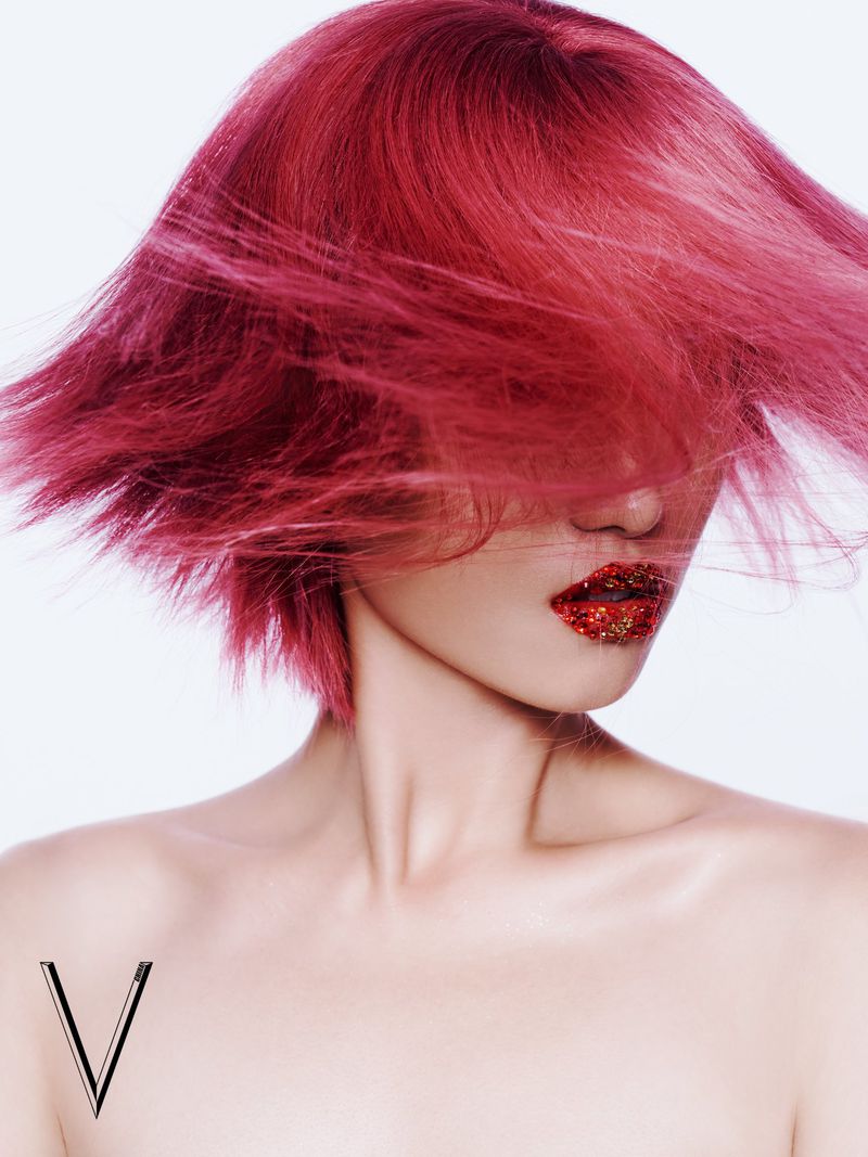 Glamour shot featuring an adult woman with pink hair and glittery red lips against a white background, highlighting hair and makeup artistry.
