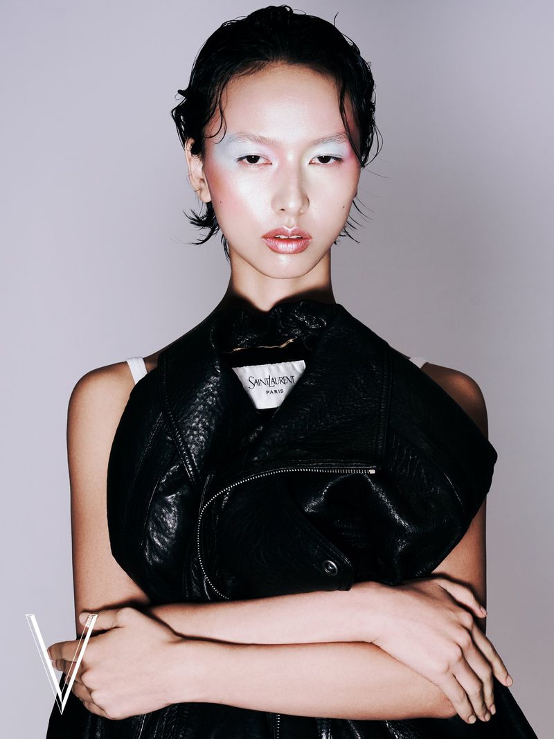 Portrait of an Asian woman with artistic makeup and a black leather jacket, posing indoors in a studio setting for a fashion editorial.