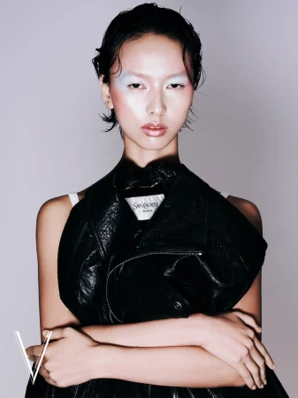 Portrait of an Asian woman with artistic makeup and a black leather jacket, posing indoors in a studio setting for a fashion editorial.