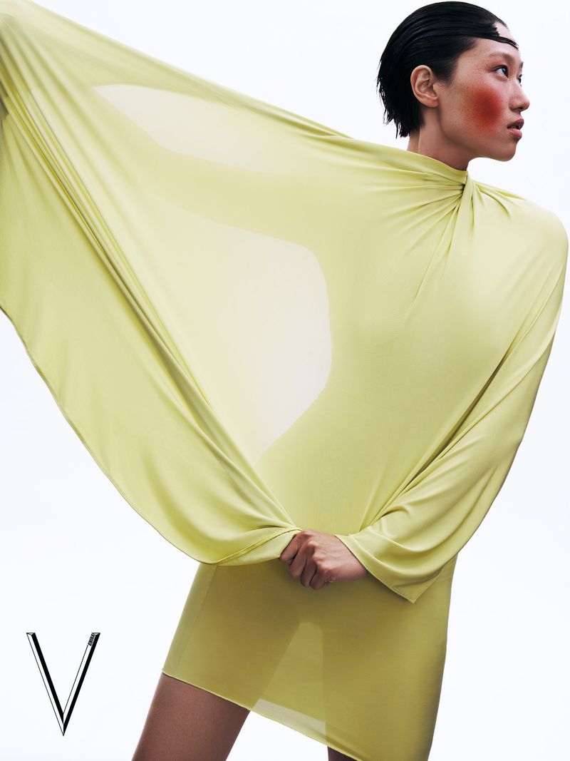 Model in a yellow dress with flowing sleeves posing against a plain white background for V Magazine China editorial.