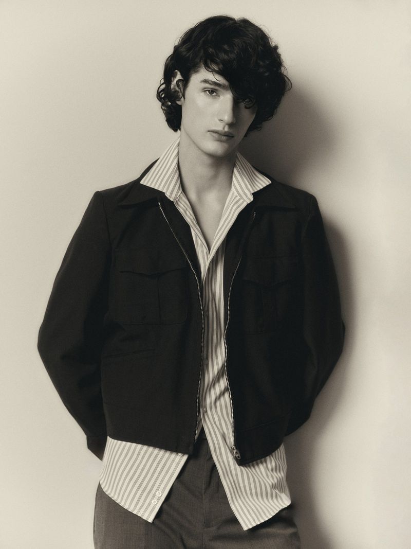 Adult male with dark hair and jacket posing in a photo studio, looking at the camera with neutral facial expression, fashion style