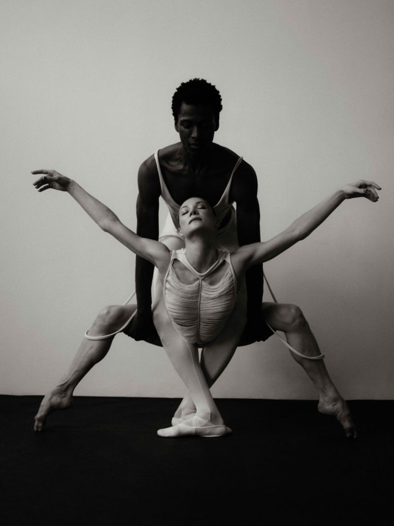 Black and white dance portrait of two ballet dancers, an African-American male and a fair-skinned female in elegant, expressive poses.