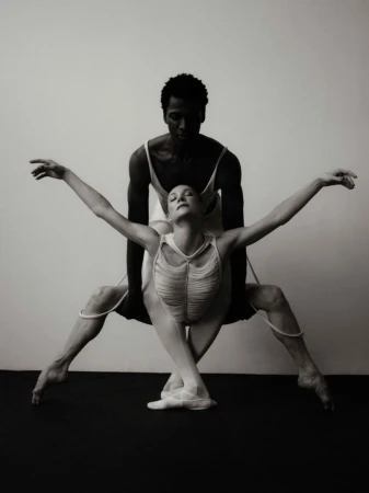 Black and white dance portrait of two ballet dancers, an African-American male and a fair-skinned female in elegant, expressive poses.