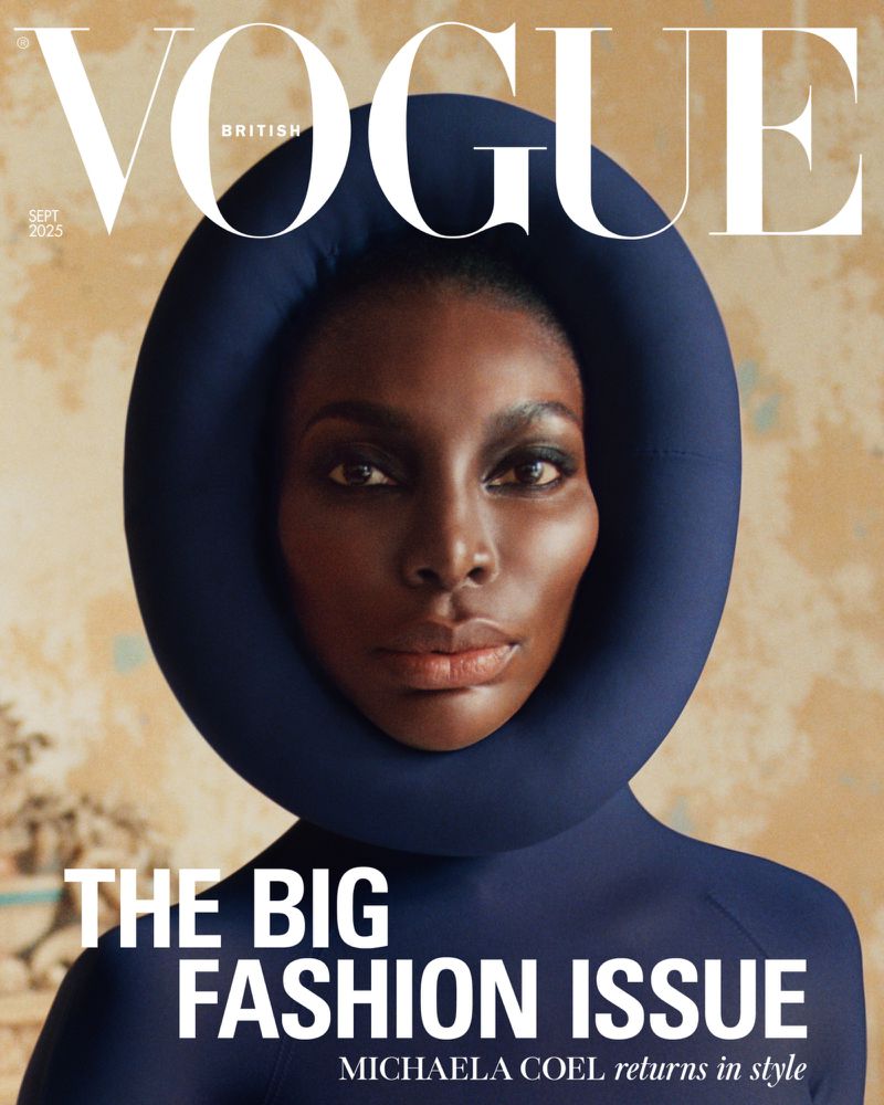 British Vogue cover featuring Michaela Coel, wearing a navy blue padded collar and dress, against a neutral patterned background.