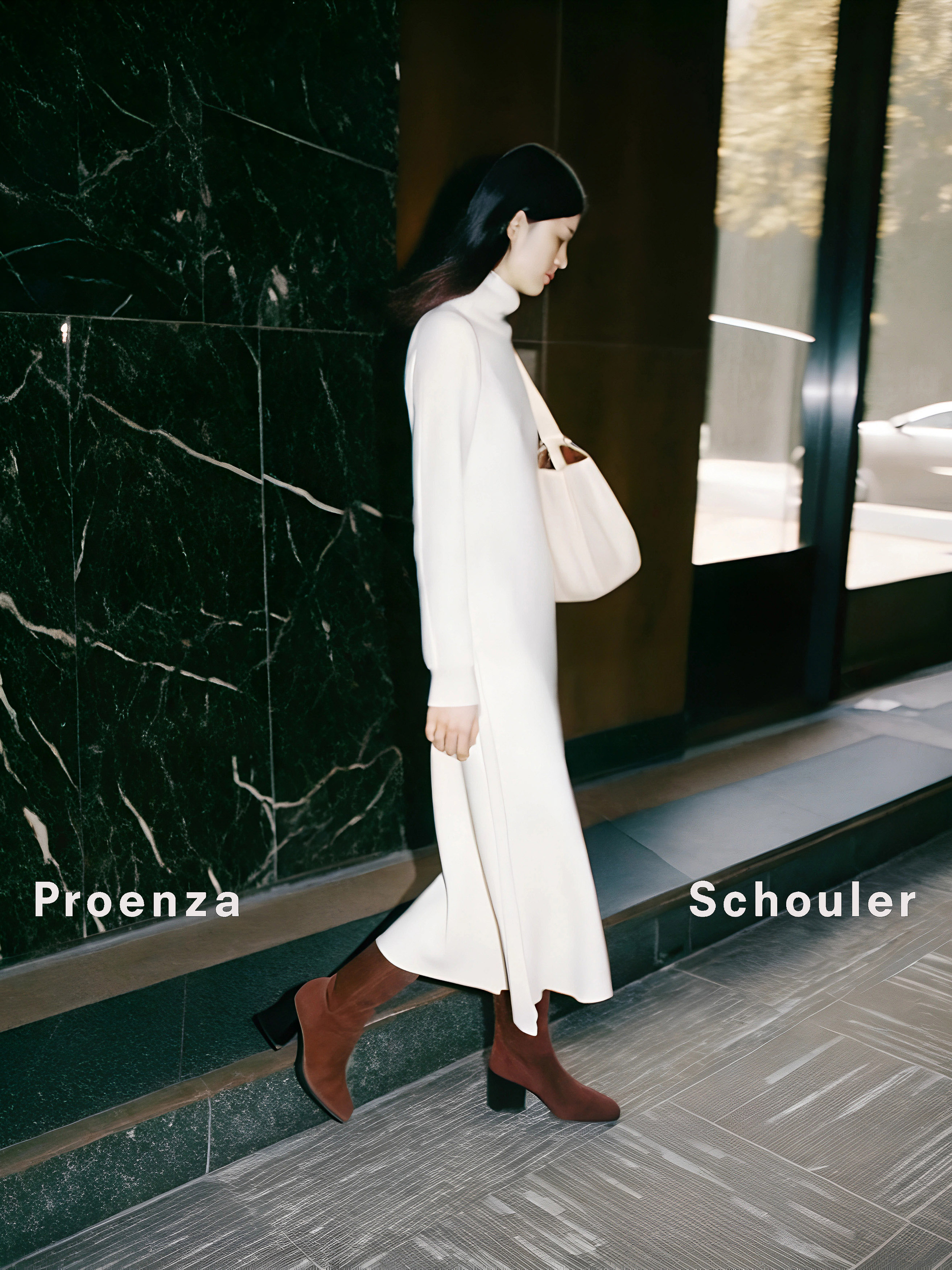 A woman in a cream dress and brown boots walks in front of a marble wall, carrying a light-colored tote bag, fashion photography.