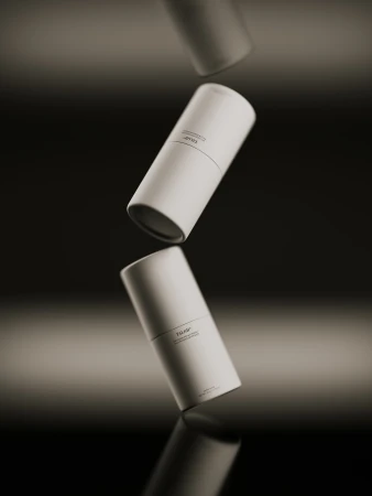 Three white cylindrical containers with product text hover against a dark background with a horizontal light reflection, product shot.