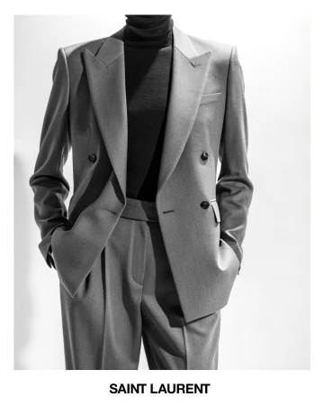 Black and white fashion shot of a grey tailored suit with a black turtleneck, in front of a white background. Saint Laurent logo visible.