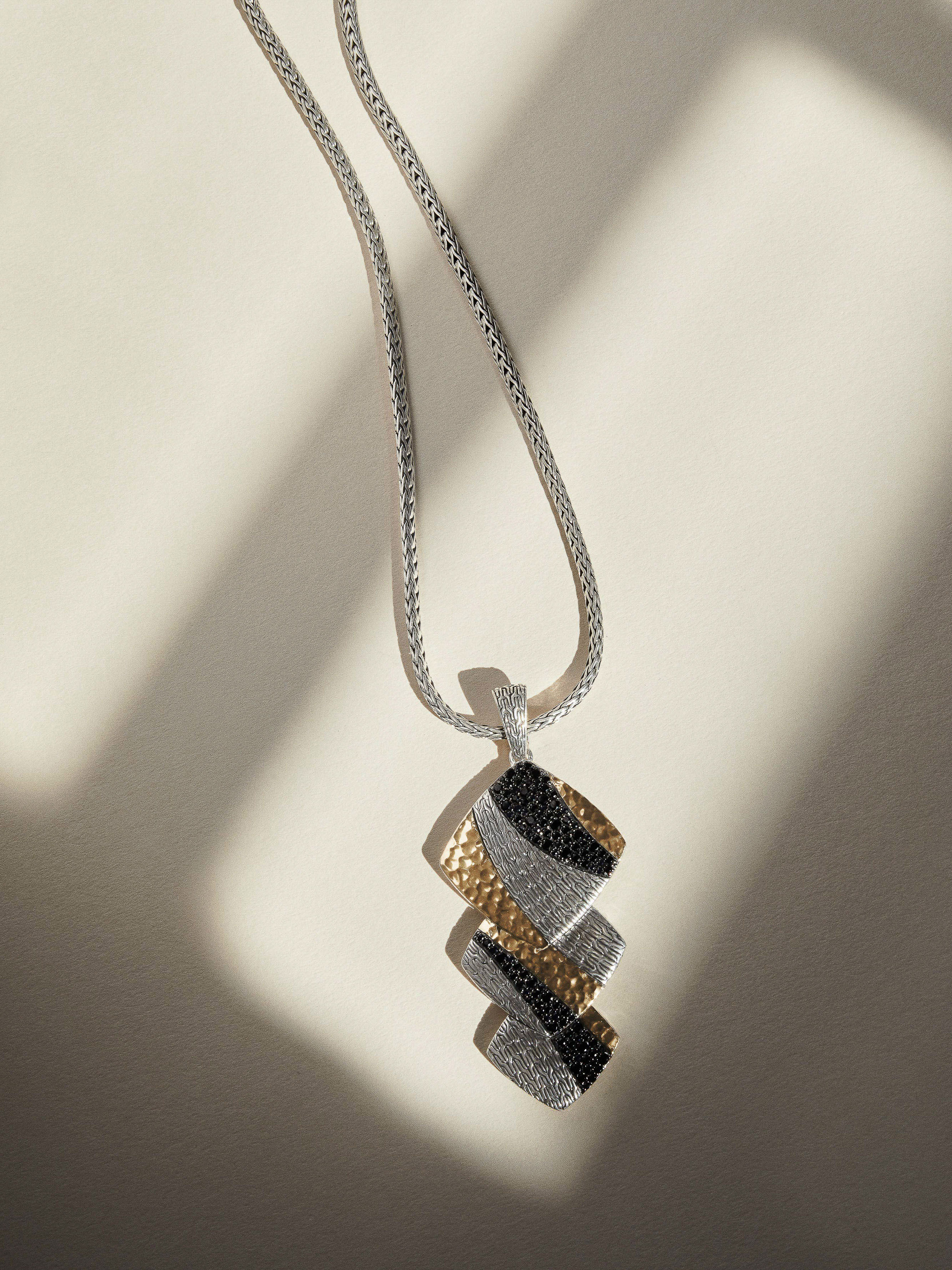 John Hardy geometric pendant necklace with hammered gold, pavé crystals, and black stones on a silver woven chain.