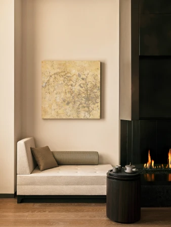 Beige modern interior with daybed, abstract art, black fireplace, and a small round table holding tea set next to wooden floor.