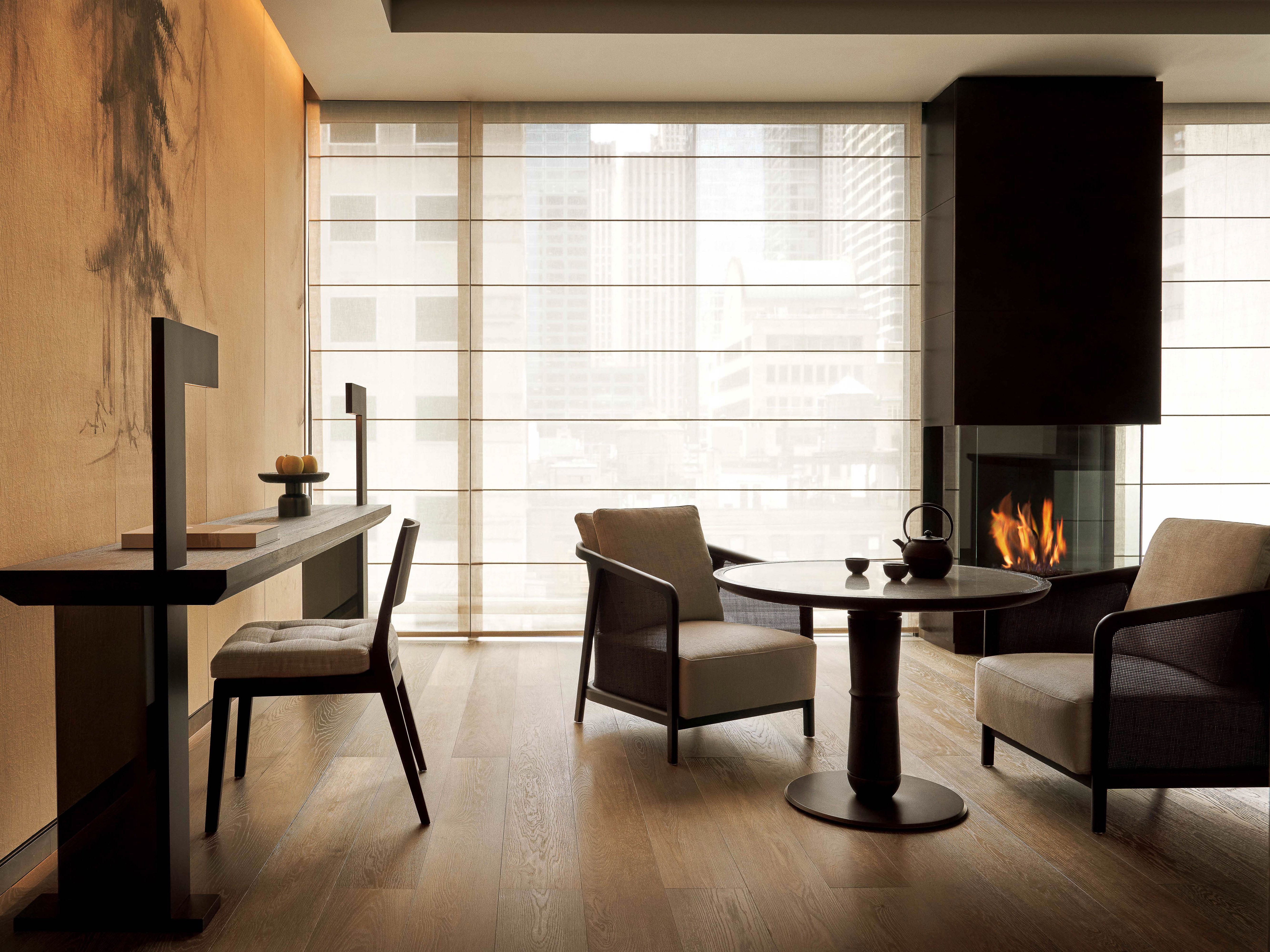 Interior of a modern living room featuring a fireplace, seating, and artwork, creating a serene and contemporary ambiance.