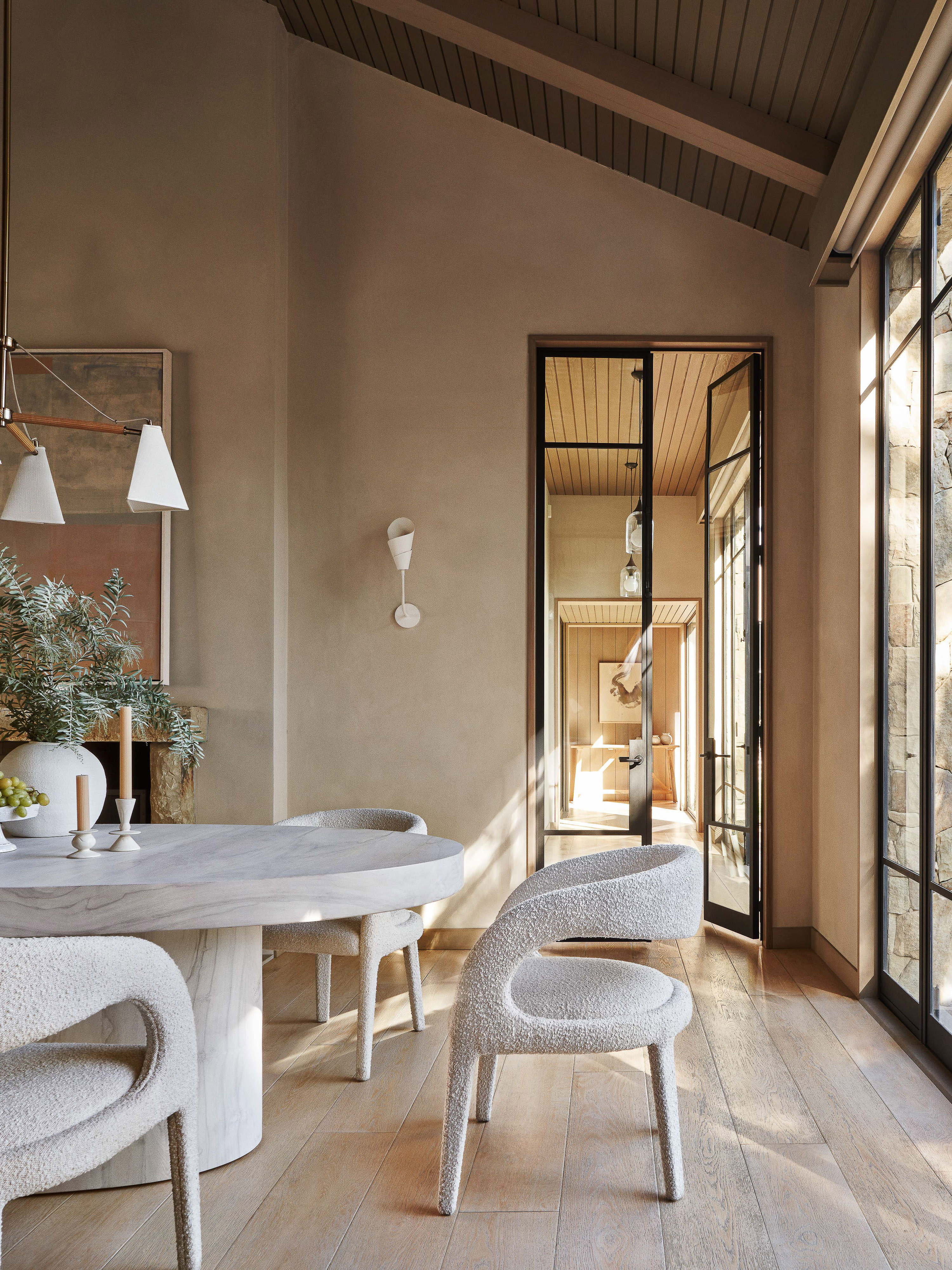 Interior shot of a modern dining room with white, rounded table and chairs, large windows, and neutral color palette for an elegant look.