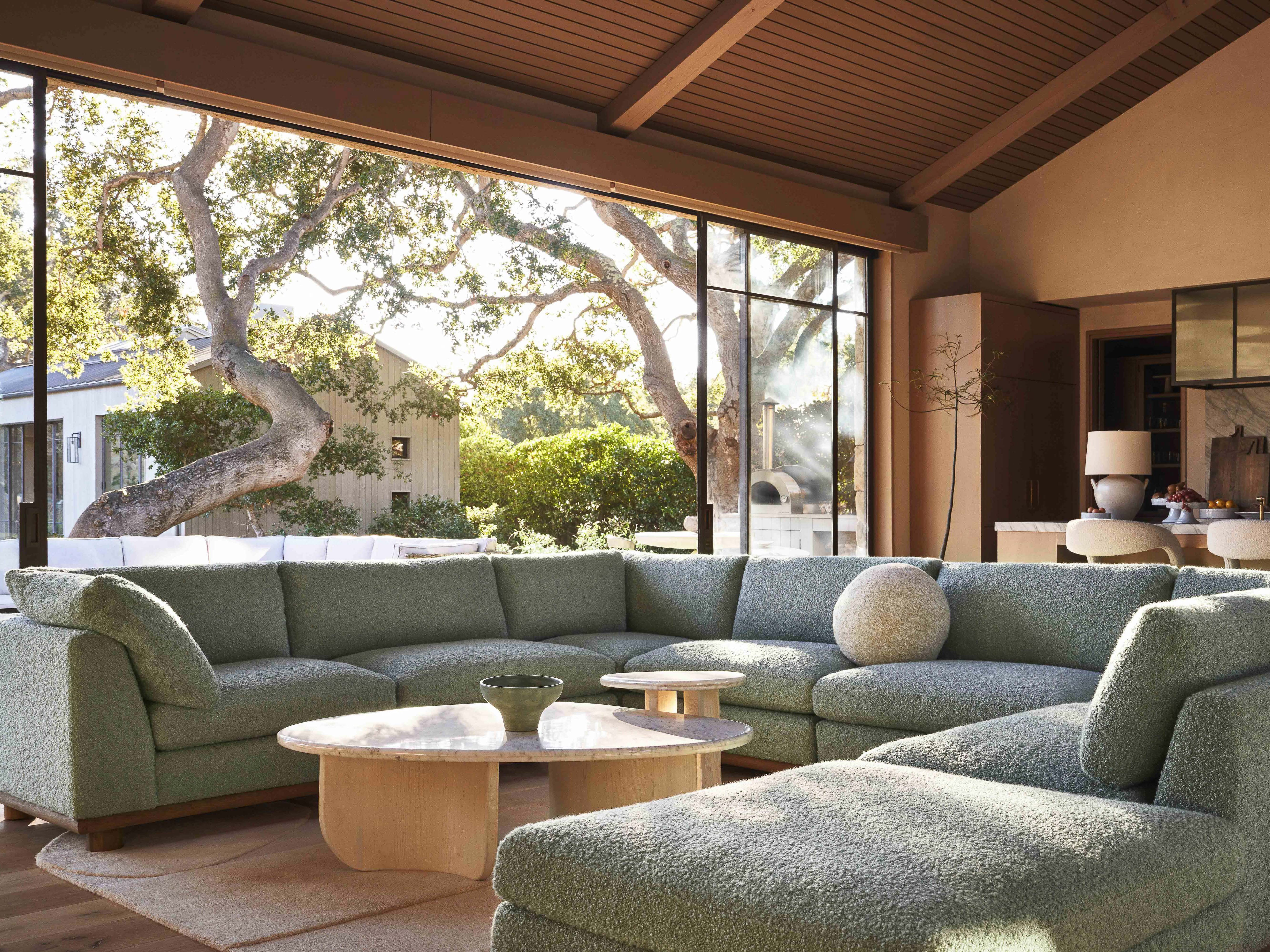 Living room with a large sectional sofa, marble coffee table, and natural light streaming through the windows, creating an inviting interior space.