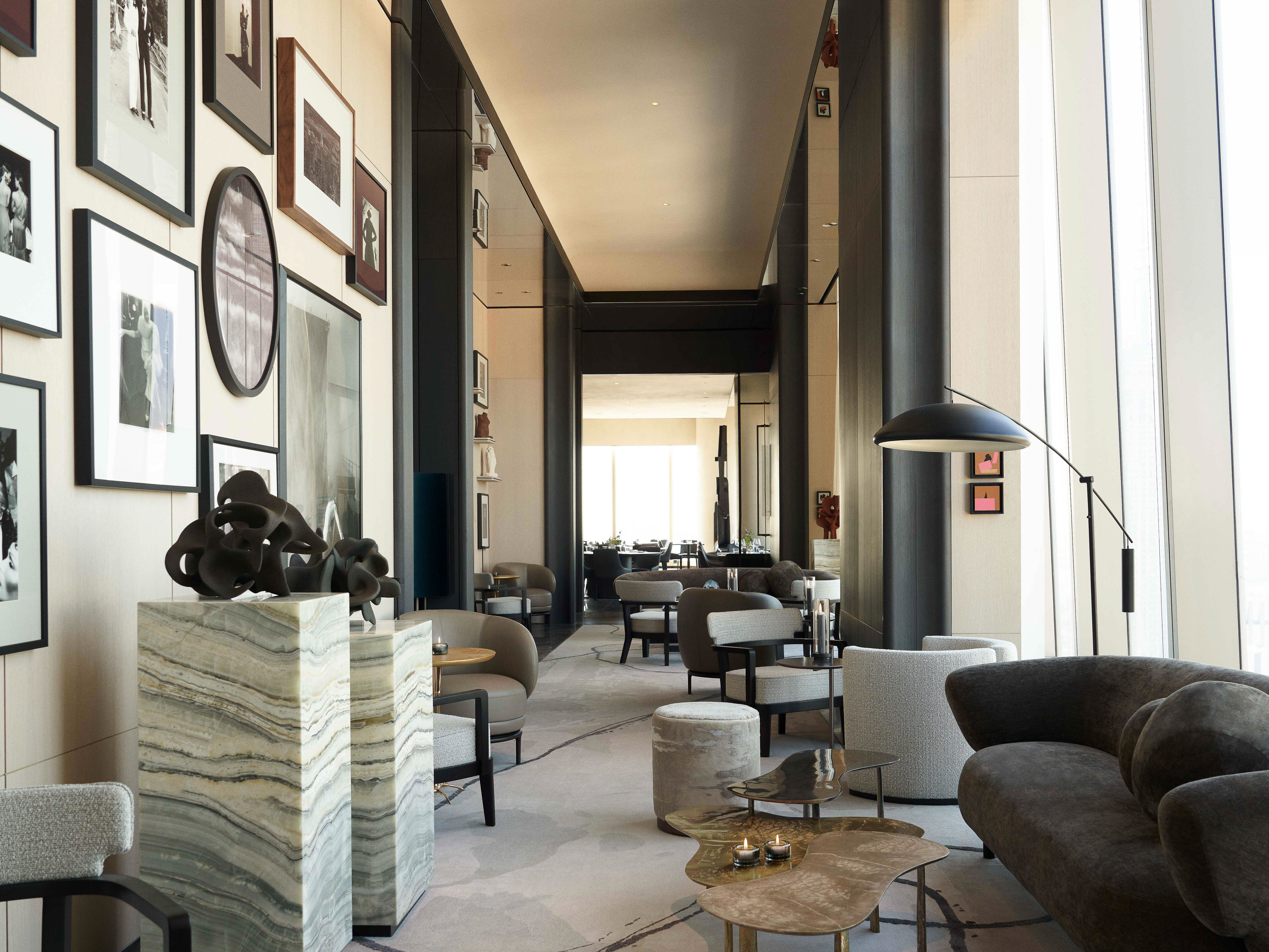 Interior design of a modern lounge area in a hotel with comfortable seating, decorative art, and a spacious, light-filled environment.
