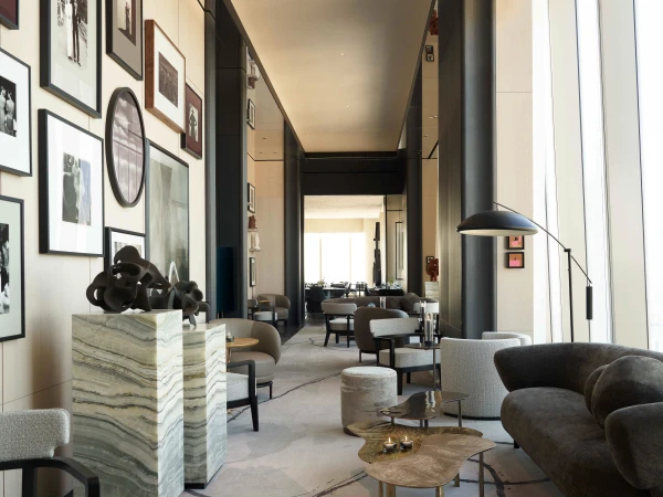Interior design of a modern lounge area in a hotel with comfortable seating, decorative art, and a spacious, light-filled environment.