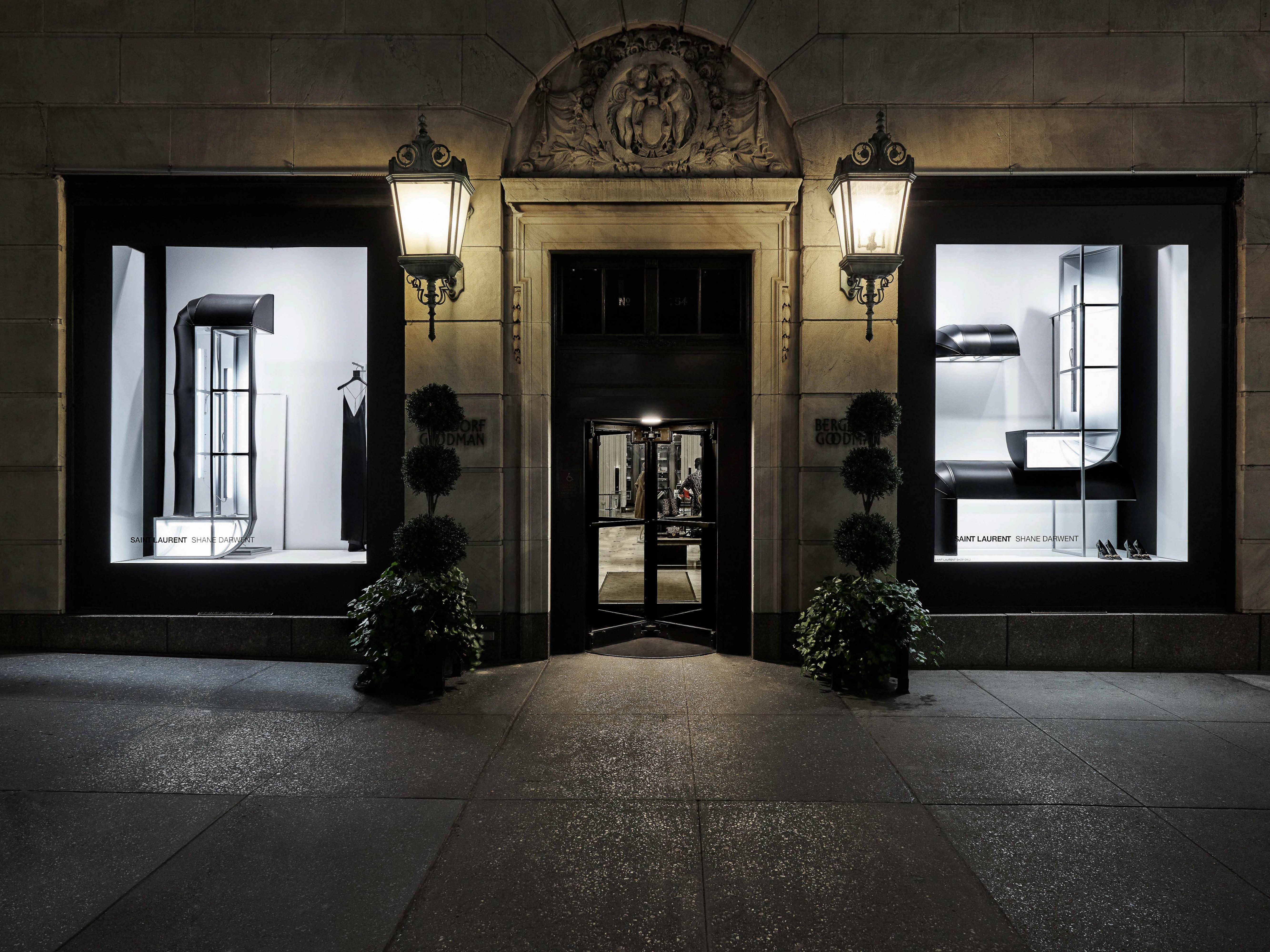 Saint Laurent store facade at night with illuminated windows, architectural details, and sidewalk, conveying upscale retail.