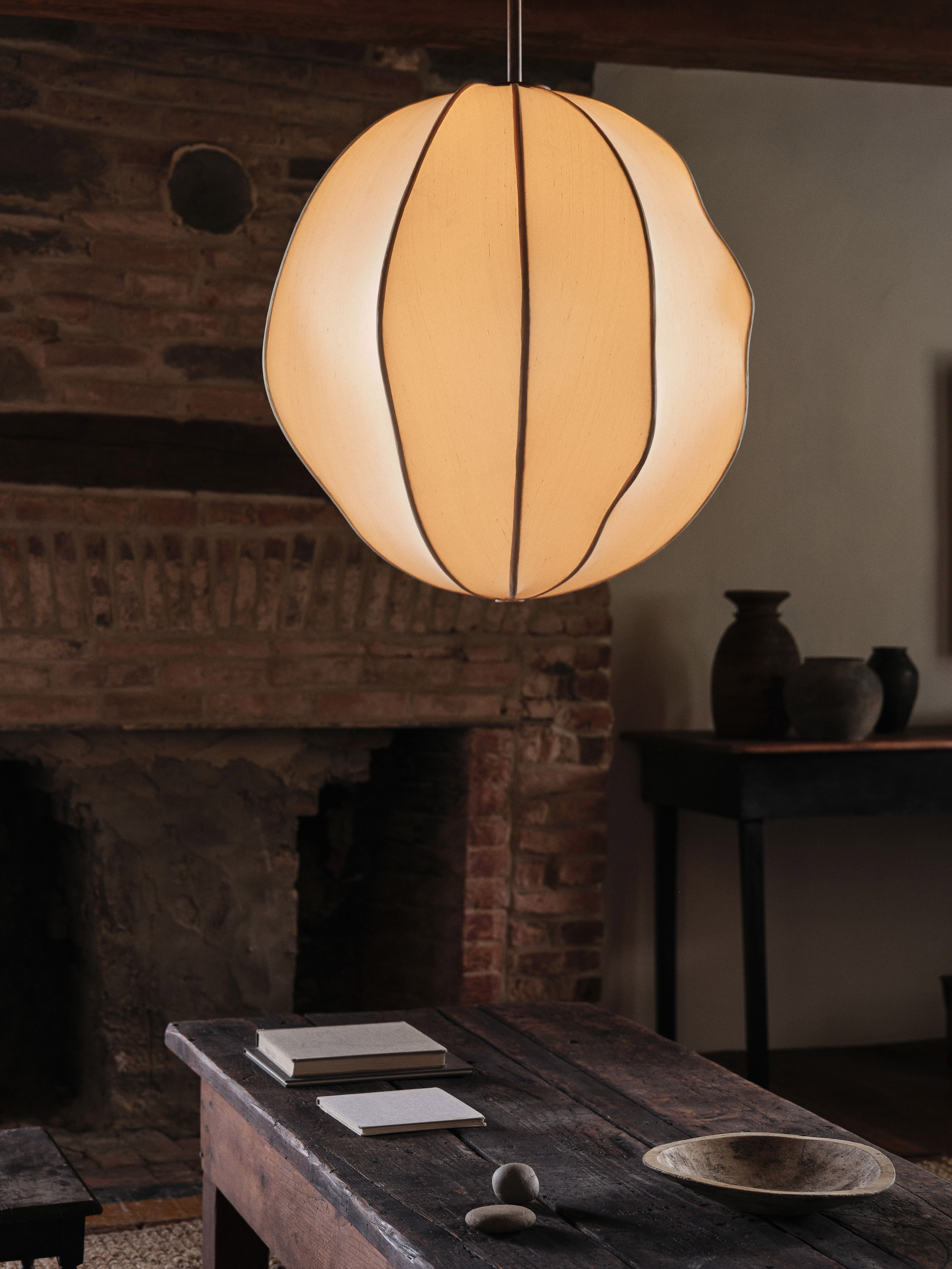 Interior shot of a room with a wooden table, textured walls, and a unique orb-shaped pendant light with dark vertical stripes.