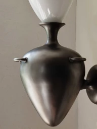 Sculptural dark metallic wall sconce fixture with a white glass diffuser shade mounted on a neutral wall.
