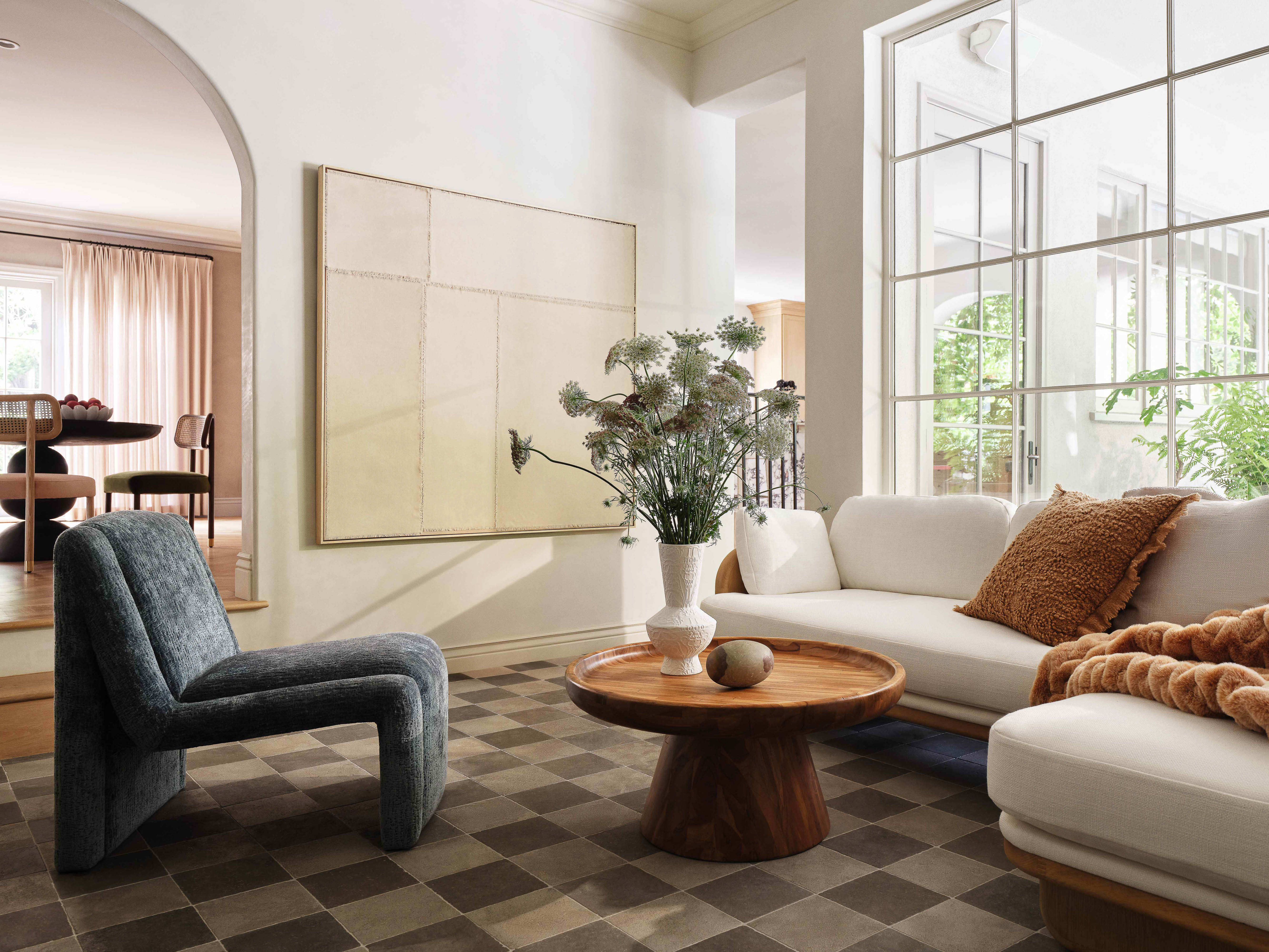 Living room interior showcasing a white sofa, blue chair, wood coffee table, and a black and white checkered rug.