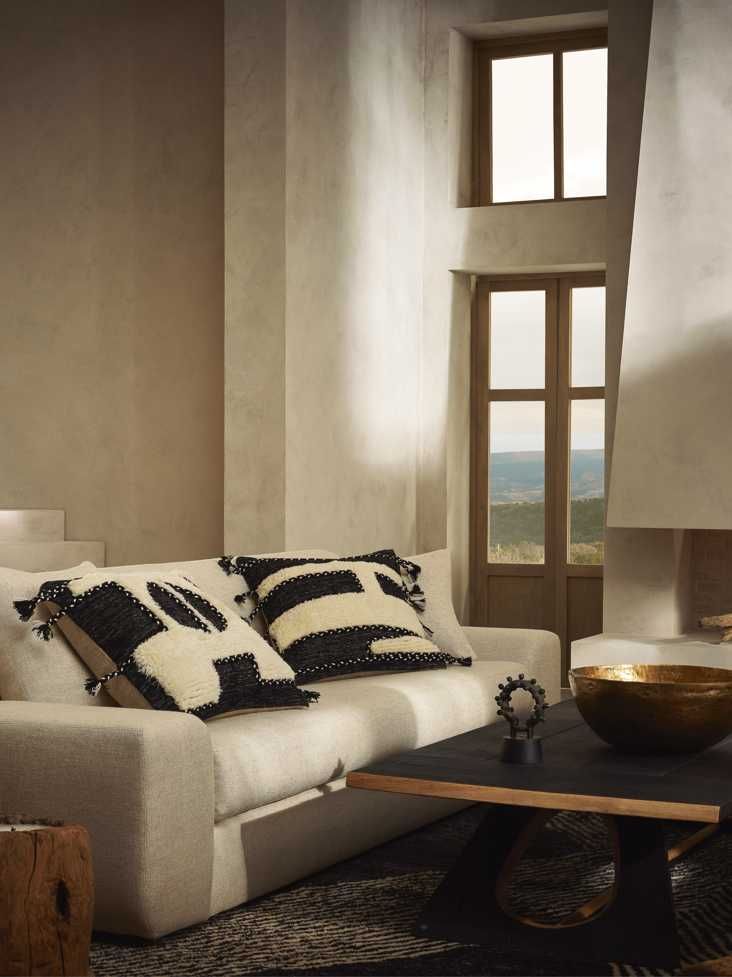Living room interior with a light beige sofa adorned with two decorative throw pillows featuring bold black-and-white geometric patterns.