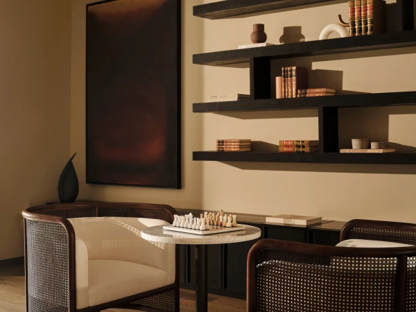 Interior design features seating near a chess set on a marble table, set against a backdrop of floating shelves with decorative objects.