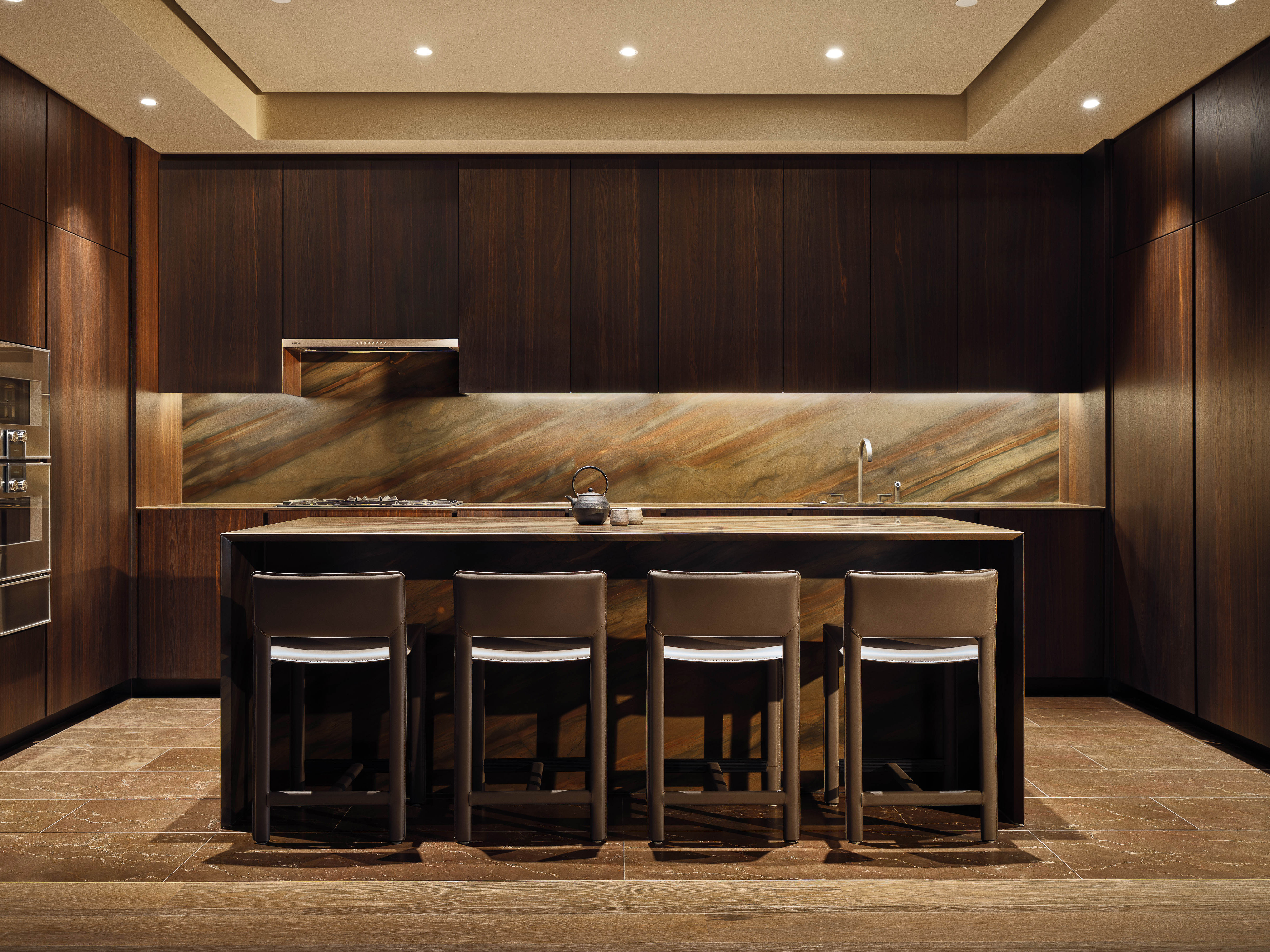 Contemporary kitchen design showcases dark wood cabinets, marble backsplash, island with bar stools, and warm recessed lighting, creating a cozy atmosphere.