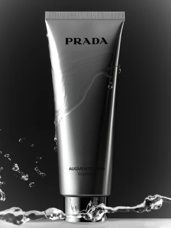 Prada skincare product in a silver tube with water droplets on a black backdrop for beauty, product, skincare advertising photography.