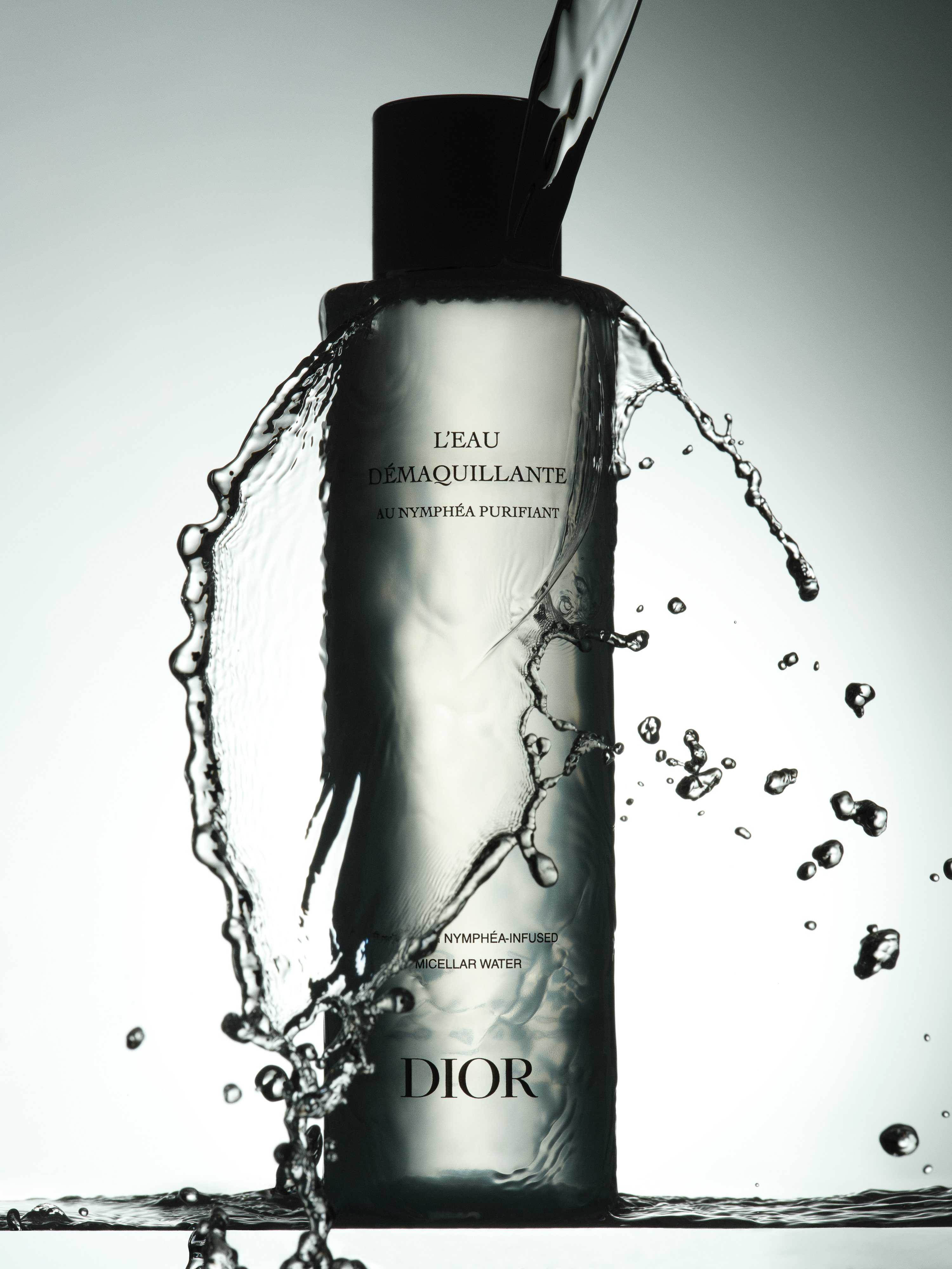 Beauty product commercial shot showcasing Dior face cleanser with water splash against a clean background for skincare advertising.