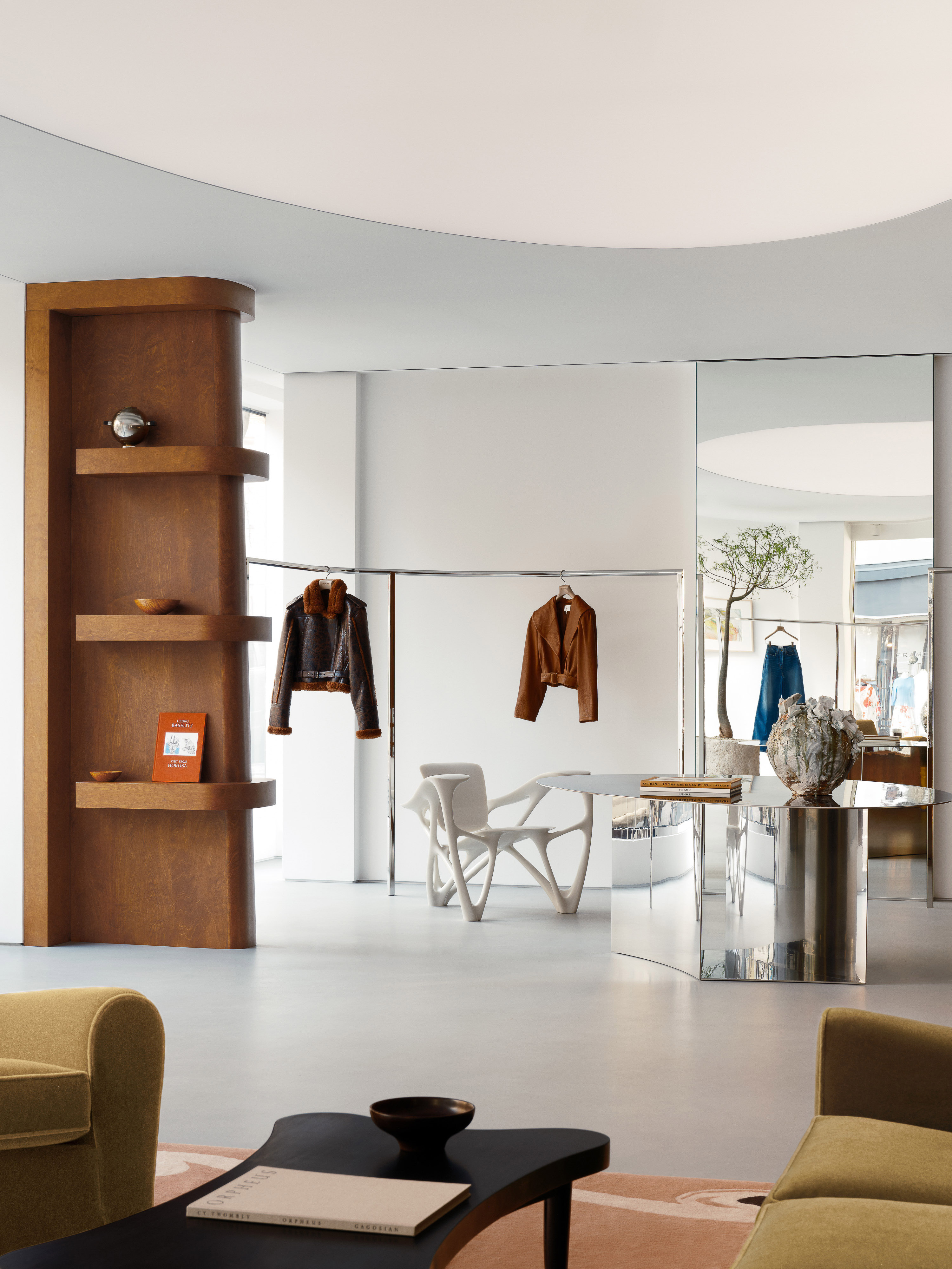 Interior of a modern fashion store with clothing racks, display shelving, minimalist furniture, and contemporary design elements.
