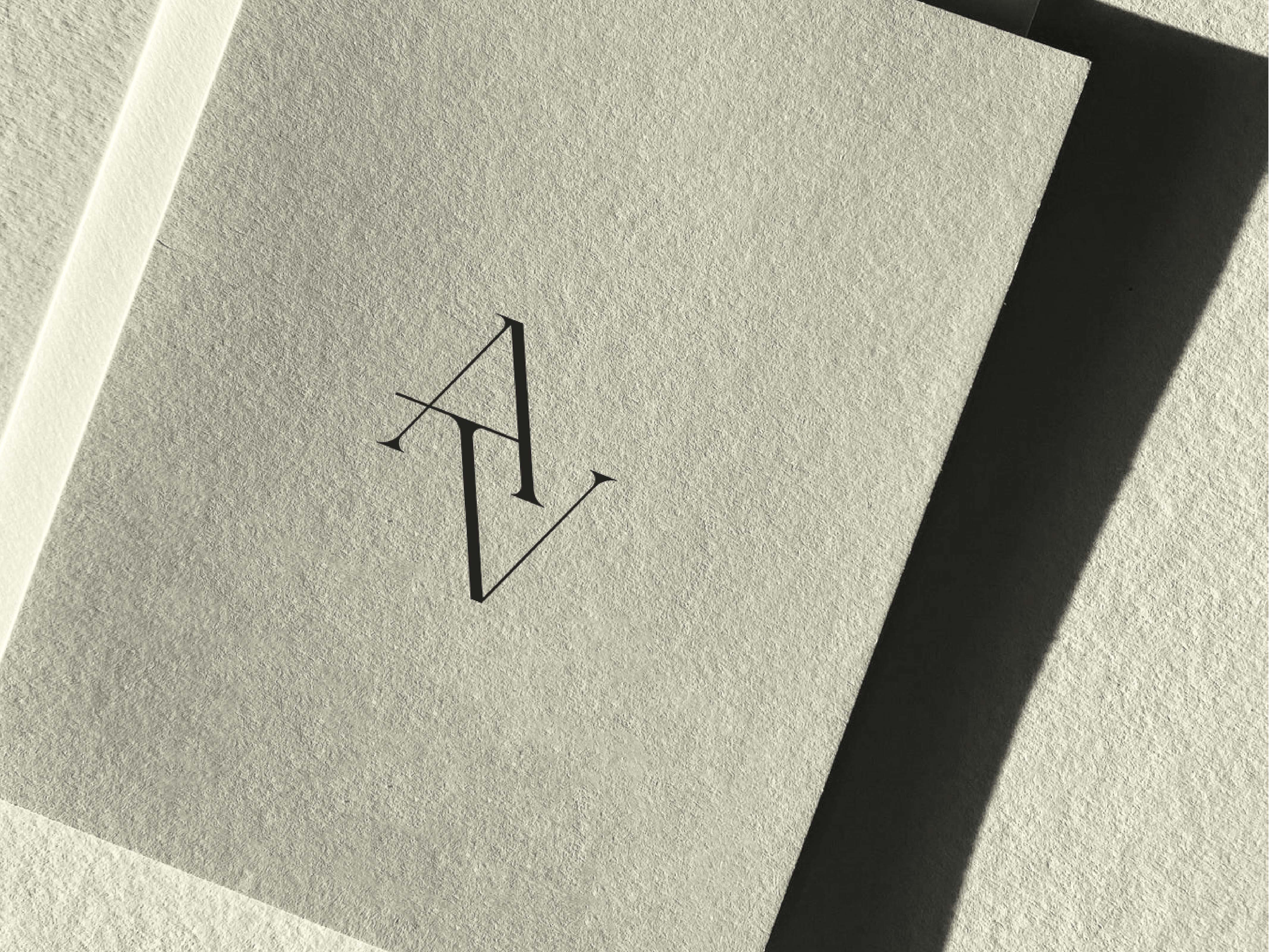 Monogram logo design featuring the letters A and V on textured paper. The logo is minimalist and modern, casting a distinct shadow.