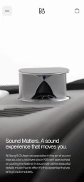 Bang and Olufsen acoustic lens car speaker mounted on an automotive dashboard with mobile website interface overlay.