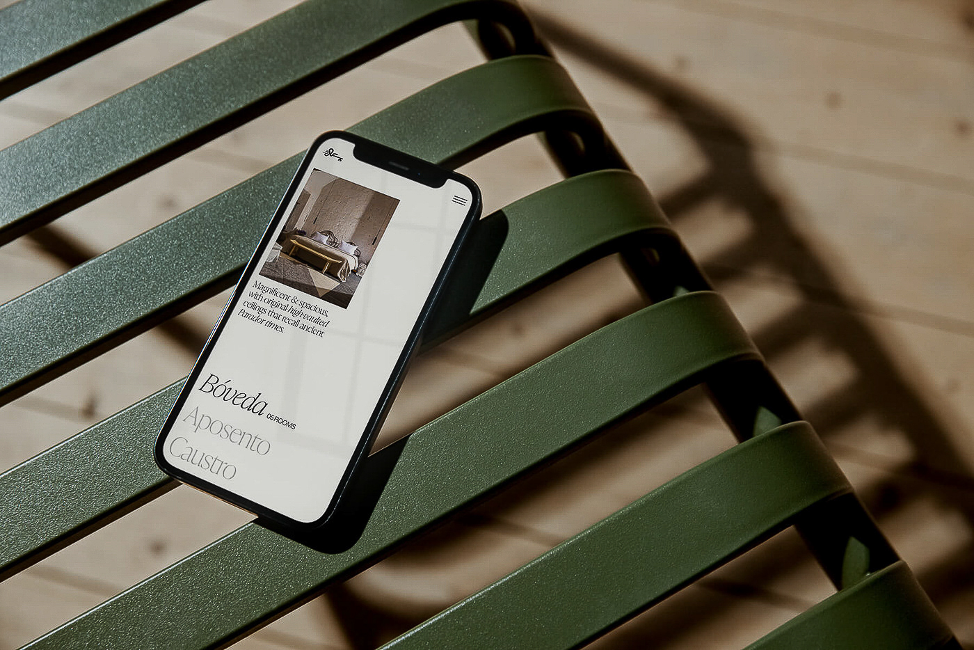 A smartphone displays a web page on a green metal chair, showcasing screen content and chair design in a modern, minimalist aesthetic.