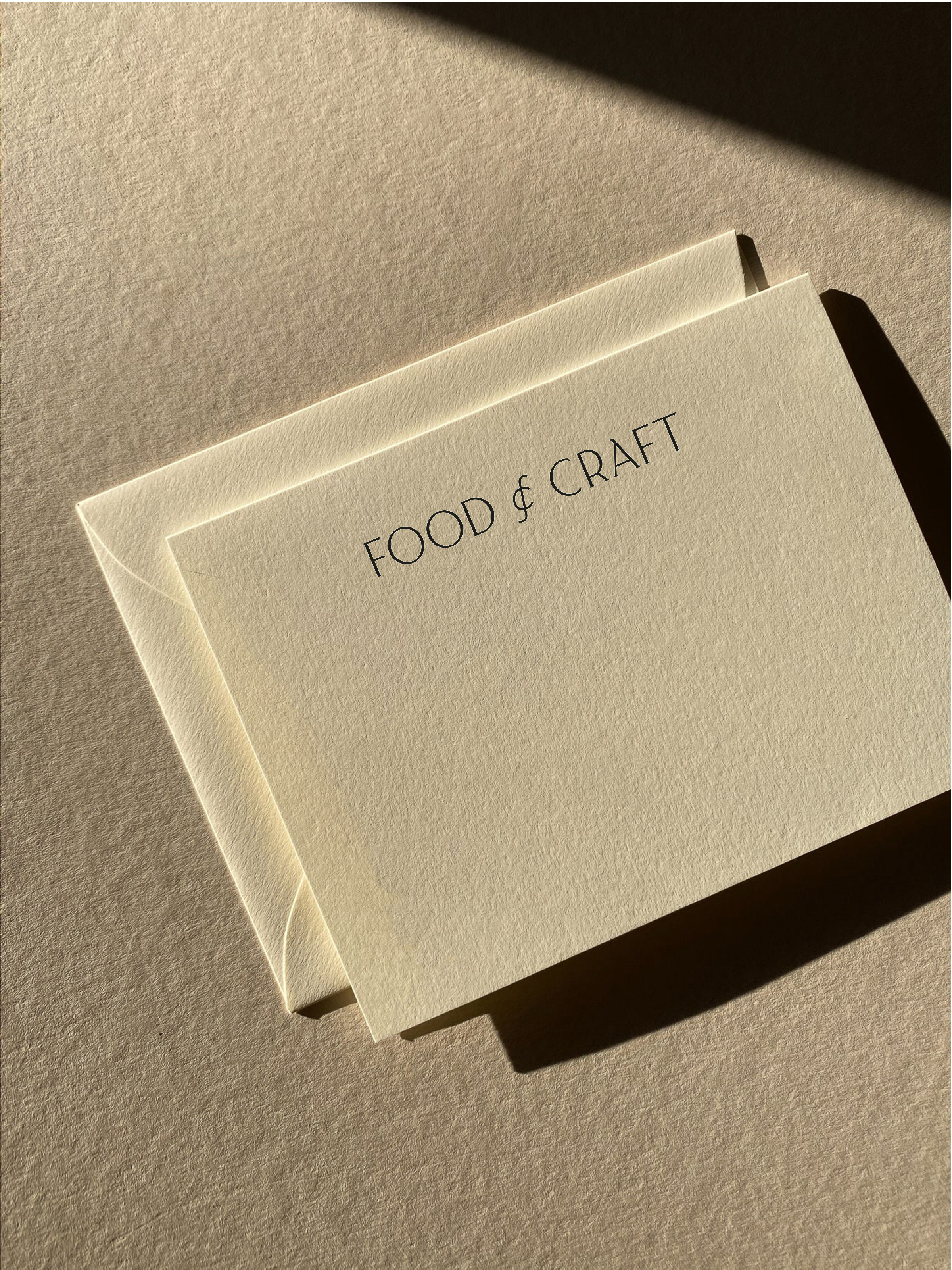 An envelope and card are displayed on a neutral surface, with the text 'FOOD & CRAFT' printed in simple, elegant font.