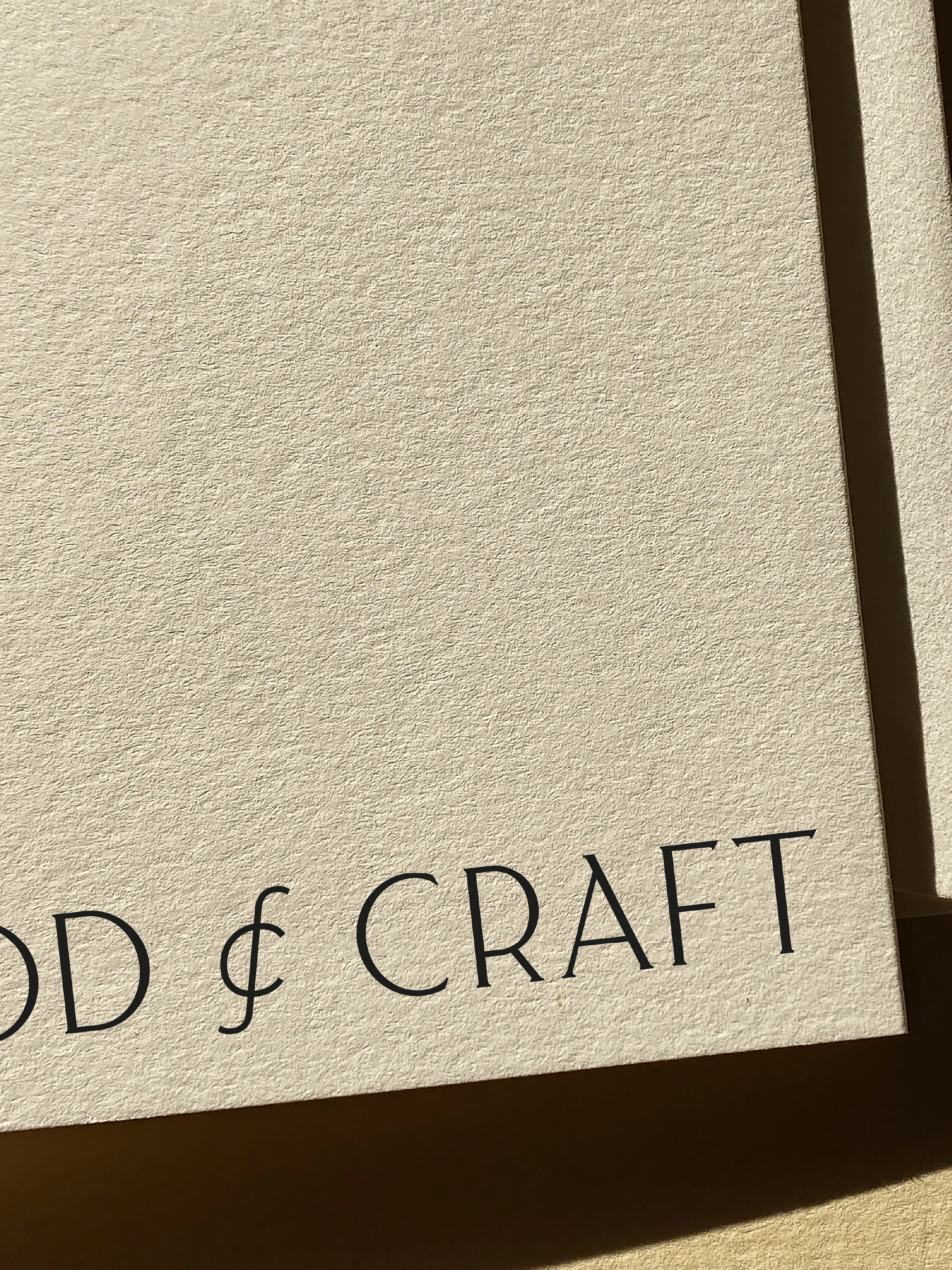 Close-up of cream-colored textured paper with the words "& CRAFT" printed in simple black font at the lower-left.
