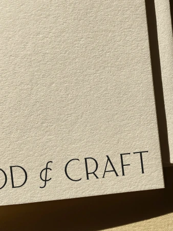 Close-up of cream-colored textured paper with the words "& CRAFT" printed in simple black font at the lower-left.