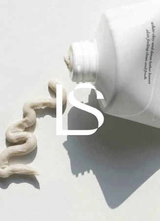 Close-up shot of a white tube with skincare cream coming out of it, swirled on a white surface, ideal for beauty product display.