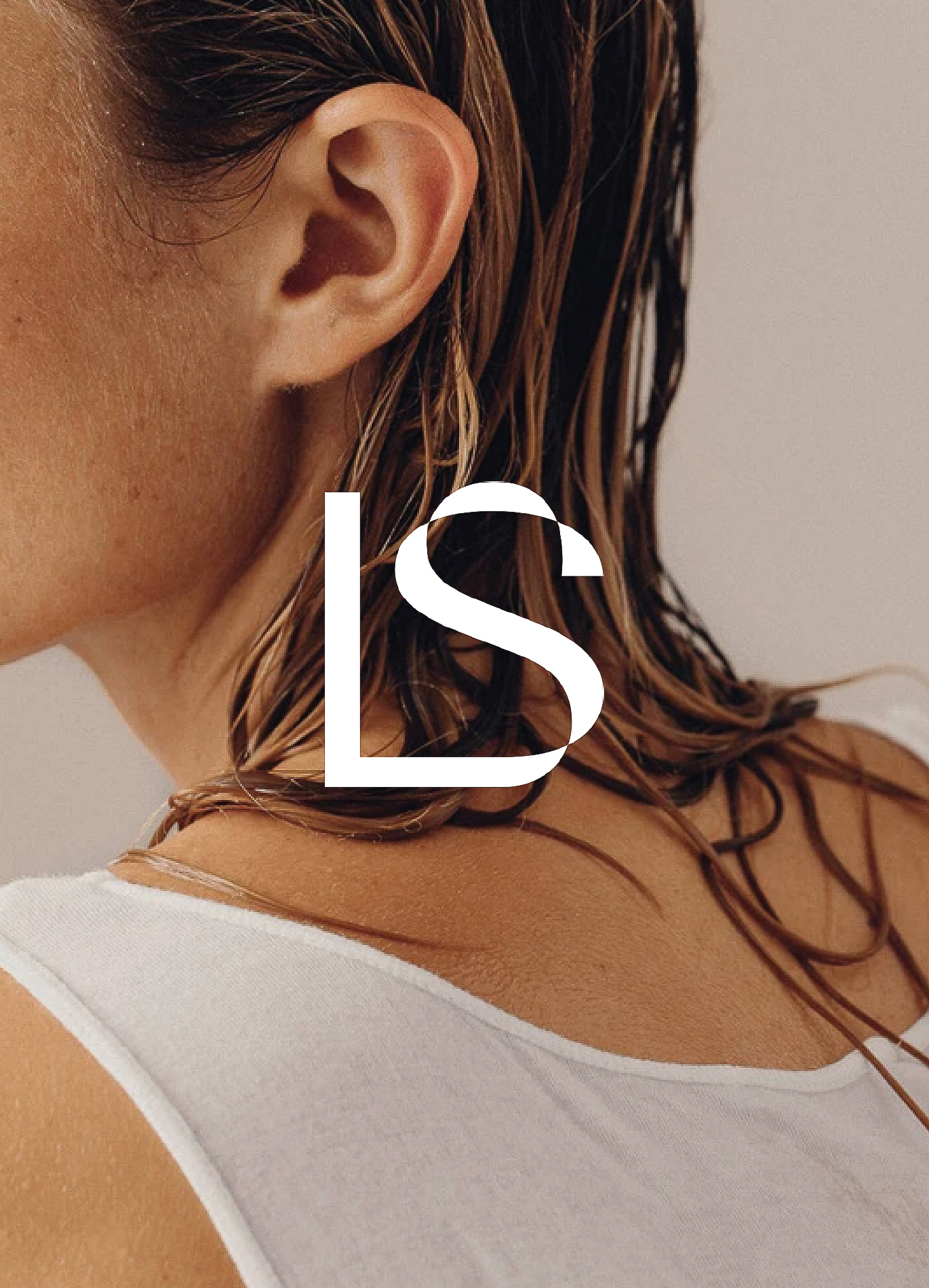Close-up portrait of a female with wet hair, visible ear, shoulder, and white top, set against a neutral background.