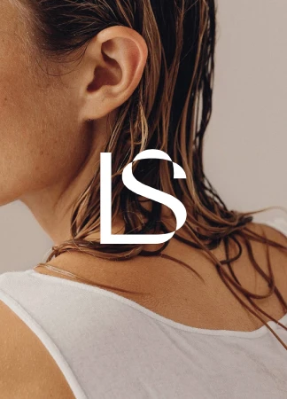 Close-up portrait of a female with wet hair, visible ear, shoulder, and white top, set against a neutral background.