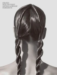 Back view of a person with glossy dark hair styled into two symmetrical rope braid pigtails against a grey studio backdrop.