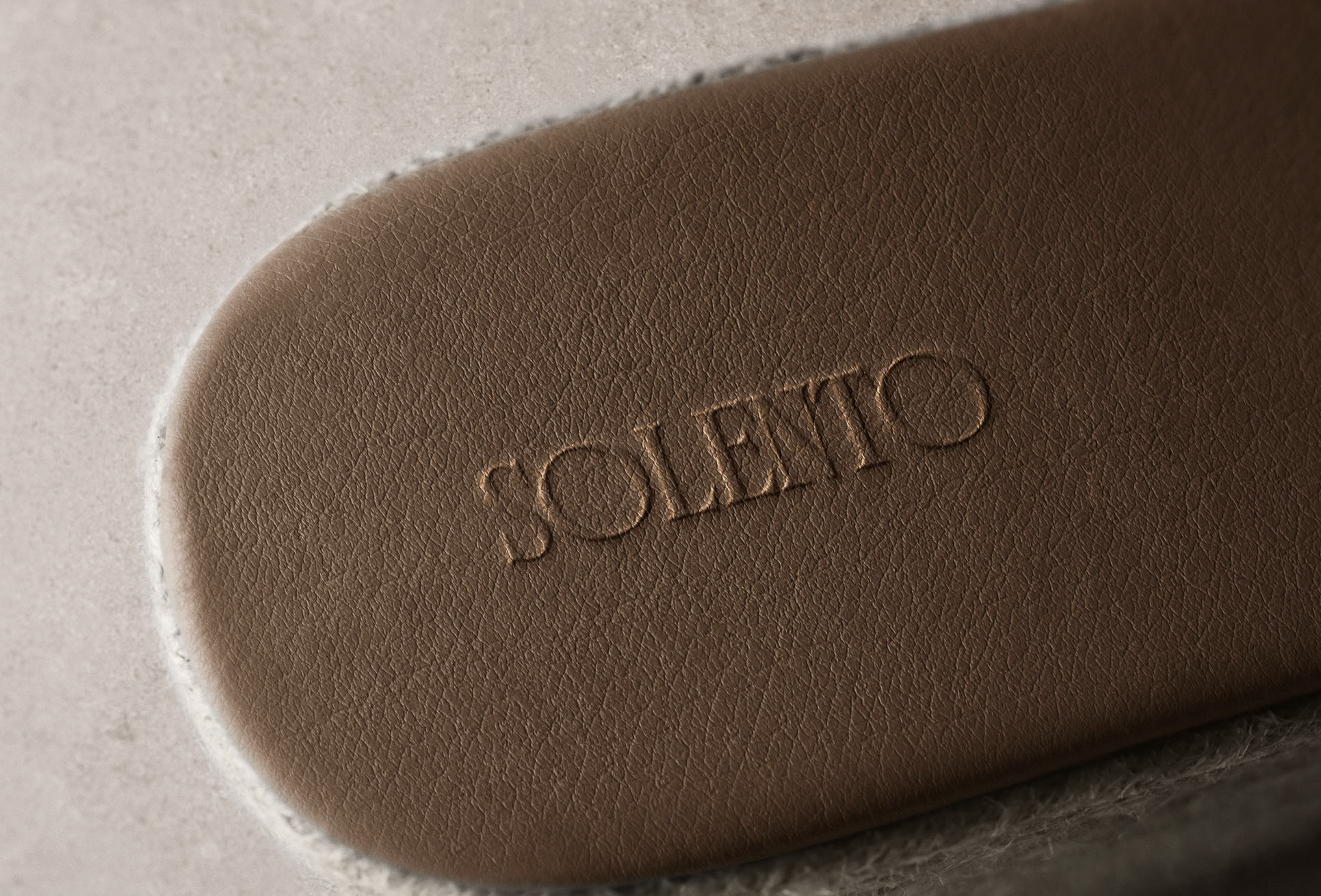 Close-up of a light brown leather insole with the embossed word 'SOLENTO', showcasing texture and neutral tones in a minimalist composition.