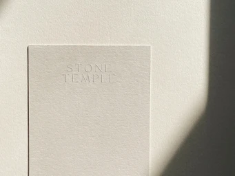 Off-white textured paper card featuring debossed Stone Temple typography resting on matching paper with a soft shadow.
