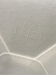 Debossed Stone Temple logo featuring an arch motif and letters S and T on textured cream paper envelope flap.