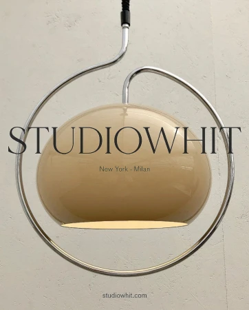 Pendant light fixture with cream-colored shade and a circular chrome support and suspension system in front of an off-white wall.