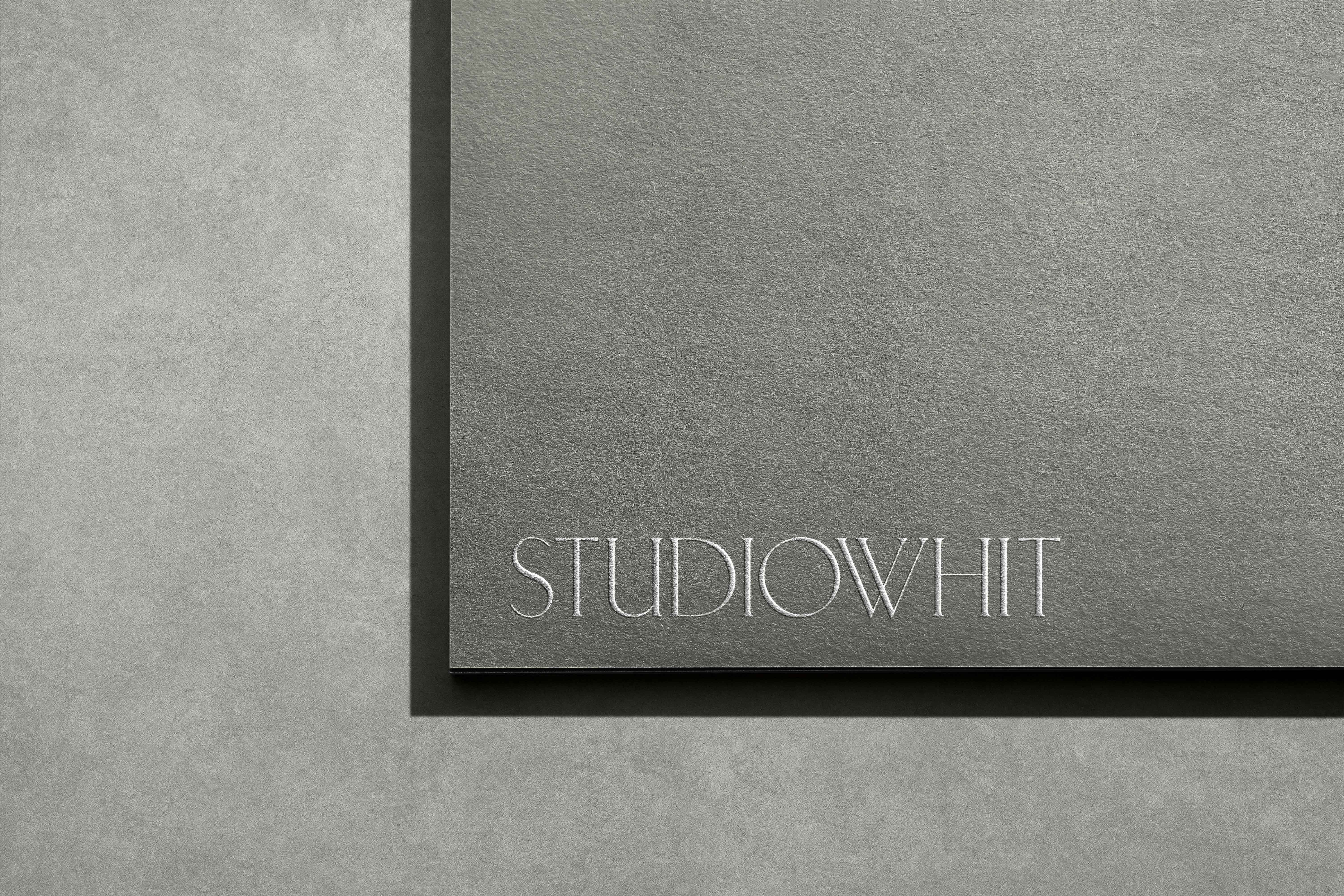 Gray card with StudioWhit logo on a textured gray surface, minimal design, neutral tones, showcasing branding and surface details.