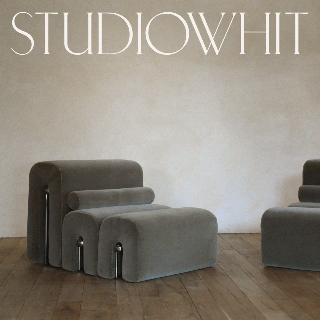 Interior photo of gray lounge chairs with metal accents on a hardwood floor against a light gray wall, showcasing minimalist furniture design.