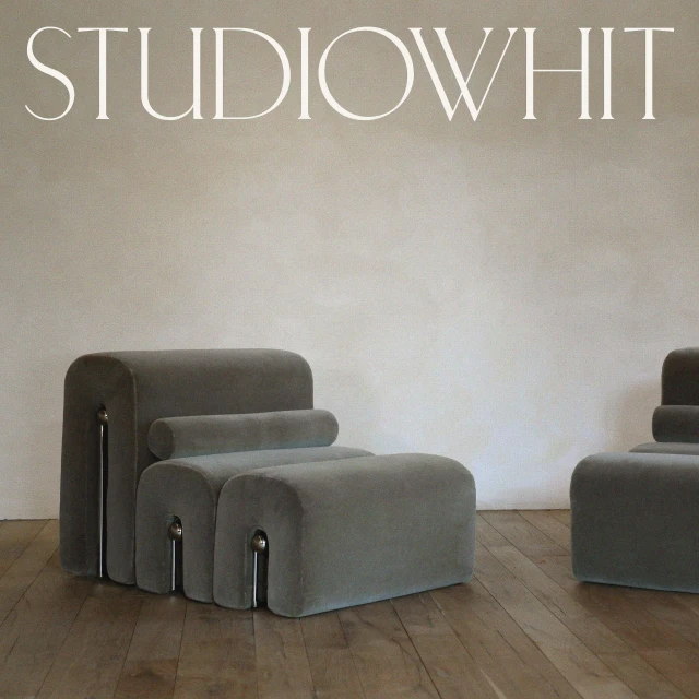 Two gray velvet modular lounge chairs and ottomans on a wood floor against an off-white wall provide modern interior design appeal.