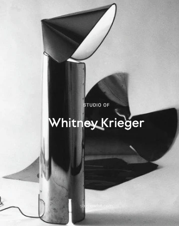 Modern chrome floor lamp with a cone-shaped shade reflecting light in a photo studio, black and white minimalist design.
